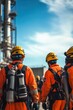 © felix_brönnimann - Workers in safety gear inspecting industrial plant against blue sky, highlighting teamwork and safety in construction and oil refinery environments.