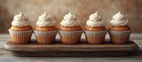 Rustic wooden platter featuring five delicious carrot cupcakes with creamy frosting, displayed beautifully against a warm textured background.