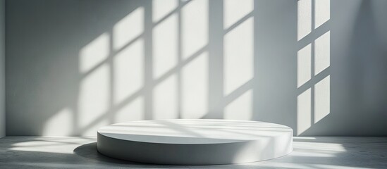 Leinwandbilder - Minimalist white circular platform bathed in soft natural light with long shadows cast across a gray wall, creating an elegant display space.