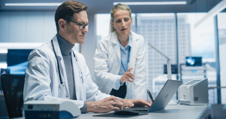 Aufkleber - Two Doctors in Hospital Office Discuss a Diagnosis, Analyzing Data on a Laptop. Male and Female Medical Professionals Talking about Treatment, Drug Prescription during Telemedicine Call