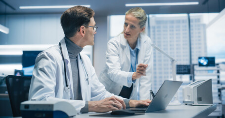 Aufkleber - Two Doctors in a.Hospital Office Analyze Patient Data on a Laptop, Discussing Diagnosis and Treatment Options in a Modern Hospital Focused on Advanced Healthcare and Successful Healthcare