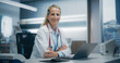 © Gorodenkoff - Expert Female Physician Works on a Laptop in a Hospital Office, Focusing on Patient Data Analysis and Medical Research in an Advanced Clinical Setting. Woman Looking at Camera