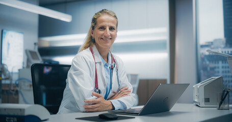 Aufkleber - Expert Female Physician Works on a Laptop in a Hospital Office, Focusing on Patient Data Analysis and Medical Research in an Advanced Clinical Setting. Woman Looking at Camera