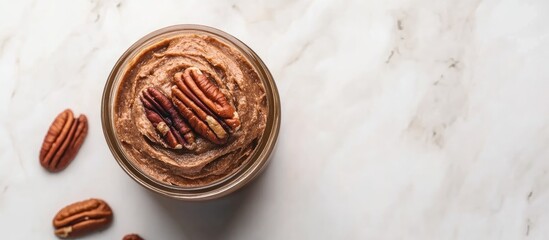 Sticker - Top view of a jar with creamy nut butter and shelled pecans set against a light mineral background with ample copy space on the right