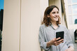 © contrastwerkstatt - Young woman with smartphone leaning against building