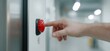 © Sebelas Studio - Hand pressing red button, factory hallway