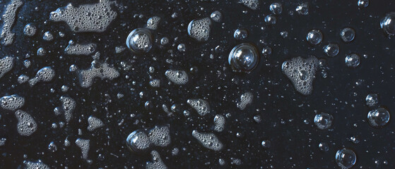 Poster - Water bubbles reflecting light on a shiny surface with a black background