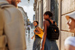© bernardbodo - Tourists walking down sunny street in european city during summer vacation