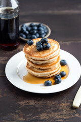 Wall Mural - Stack of pancakes with blueberries and syrup on a wooden table background