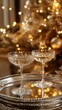 © Denys - Crystal champagne glasses gleaming on silver tray, golden bokeh Christmas tree lights casting elegant holiday ambiance
