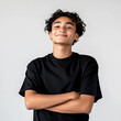 © graphic_titan - Portrait of a smiling young man with curly hair arms crossed wearing a black t-shirt against a light gray background conveys confidence and positivity