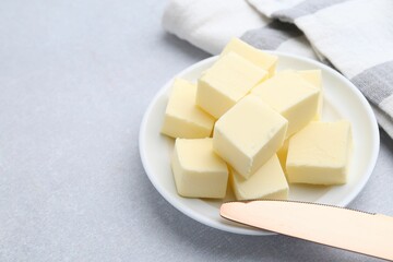 Wall Mural - Pieces of fresh butter and knife on white table, closeup. Space for text