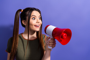 Wall Mural - Excited young woman holding a red megaphone against a solid purple background, expressing joy and enthusiasm