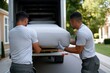 © Milos - Two strong men in matching shirts are lifting a mattress out of a moving truck, demonstrating teamwork and effort during a relocation or delivery process in the daylight.