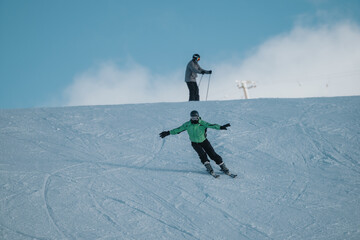 Two individuals skiing on a snowy slope with clear skies and a vibrant atmosphere, highlighting nature, sport, and an outdoor winter adventure.