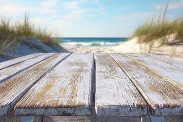 Wall Mural - Weathered wooden table overlooks a serene beach with soft waves and grassy sand dunes during a bright day