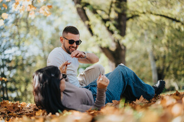 Canvas Print - A joyful couple enjoys a playful moment in a sunlit park surrounded by colorful autumn leaves, expressing happiness and connection.