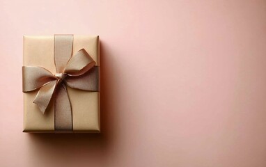 Wall Mural - Gift box with golden ribbon on soft pink background creating a warm and festive atmosphere