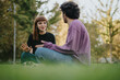 © qunica.com - A young couple sits on the grass, enjoying a lively conversation in a park filled with sunlight and greenery. Their relaxed posture suggests a comfortable and casual dialogue.
