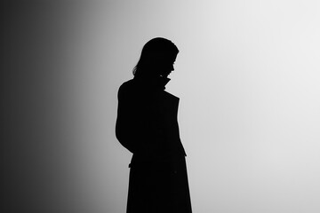 Wall Mural - A woman is standing in a dark room with a coat on