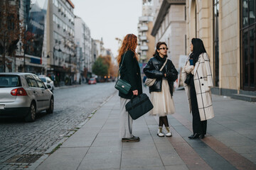 Wall Mural - Three stylish women interact on a city sidewalk with modern buildings in the background.