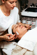 © Dusko - Close up portrait of beautician's hand massaging patient's face with jade roller at spa salon. Beauty woman face skin care. Modern beauty SPA and cosmetics concept.