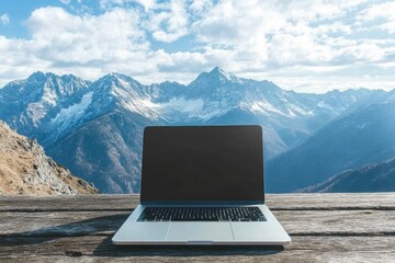 Poster - Silver Laptop with Mountain Desktop Background on Wooden Table . A laptop rests on a wooden table, with majestic mountains visible in the background, creating a serene work environment.