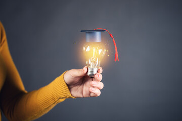 Canvas Print - light blub with graduation cap on hand woman