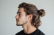 © Michael - Close-up profile of a young man with long brown hair tied in a bun, highlighting his facial features and hairstyle against a simple background