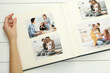 © New Africa - Woman with different photos in open photo album at white wooden table, top view