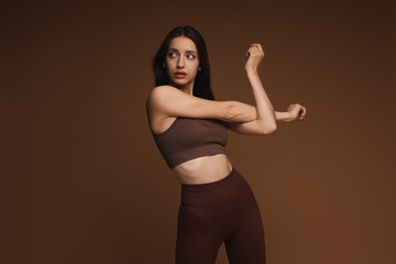 Wall Mural - Beautiful woman in stylish sportswear on brown background