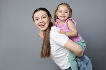 Wall Mural - Portrait of happy mother and her cute little daughter on grey background, space for text