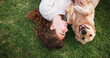 © Siphosethu/peopleimages.com - Woman, relax and lying with dog above on grass field for bonding, love and support at park. Top view, female person or pet owner with labrador or golden retriever or smile for companionship in nature