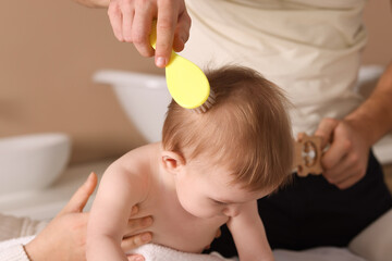 Wall Mural - Parents brushing hair of their little baby indoors, closeup