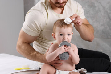 Wall Mural - Man brushing hair of his little baby indoors, closeup