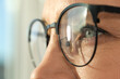© New Africa - Woman wearing stylish glasses on blurred background, closeup