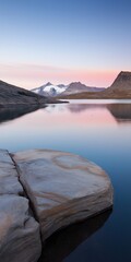 Wall Mural - A rocky shoreline with a body of water in the background. The water is calm and the sky is a beautiful pink color