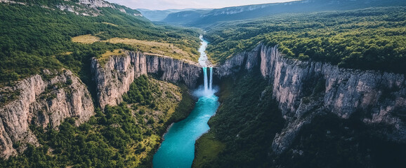 Poster - A breathtaking aerial view of a waterfall cascading into a turquoise river surrounded by lush greenery and steep cliffs, symbolizing natural beauty, serenity, and outdoor exploration.