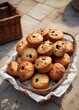 © JKLoma - Old-fashioned cinnamon raisin muffins arranged in a vintage wicker basket on a stone patio, cobblestone, garden, outdoor furniture