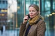 © Hunman - Serious businesswoman talking on her phone while standing in front of a glass building.