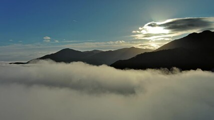 Wall Mural - flying between the clouds. aerial view of clouds, sun, and mountains at sunrise. traveling by air ba
