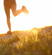 © peopleimages.com - Fitness, person and legs with running outdoor for marathon training, healthy body and cardio endurance. Athlete, lens flare and exercise on low angle for morning jog, workout performance or challenge