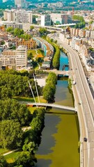 Wall Mural - Vertical video. Ghent, Belgium. Keizerpark - City park. Esco (Scheldt) river embankment. Panorama of the city from the air. Cloudy weather, summer day, Aerial View, Departure of the camera. Rich colo