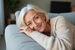 © SimpleDesignStudio - A Joyful Evening at Home: A Smiling Senior Woman with Grey Hair Relaxing Comfortably on a Sofa in a Cozy Living Room, Reflecting Contentment and Warmth