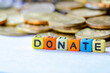 © JeromeMaurice - Donate text on colorful plastic alphabet with golden coins background