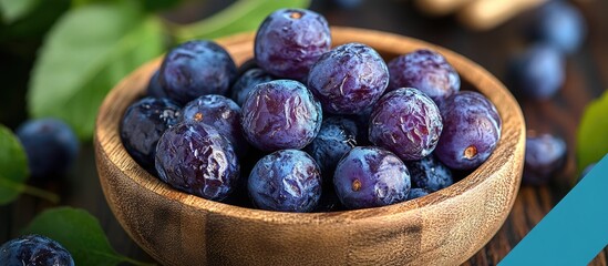 Aufkleber - Fresh blueberries in a wooden bowl on a rustic surface with green leaves and blurred background Copy Space