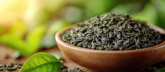 Poster - Dried green tea leaves in a wooden bowl with fresh tea leaves in the background and soft lighting Copy Space