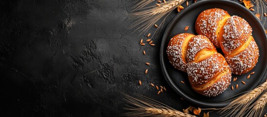 Poster - Freshly baked golden pastries on a black textured background with wheat grains and seeds Copy Space