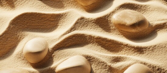 Poster - Smooth stones on wavy sand surface with textured patterns and soft shadows