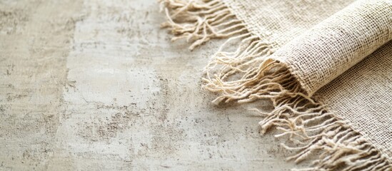 Poster - Textured beige fabric with fringes on a light neutral background displaying copy space for adding text or designs
